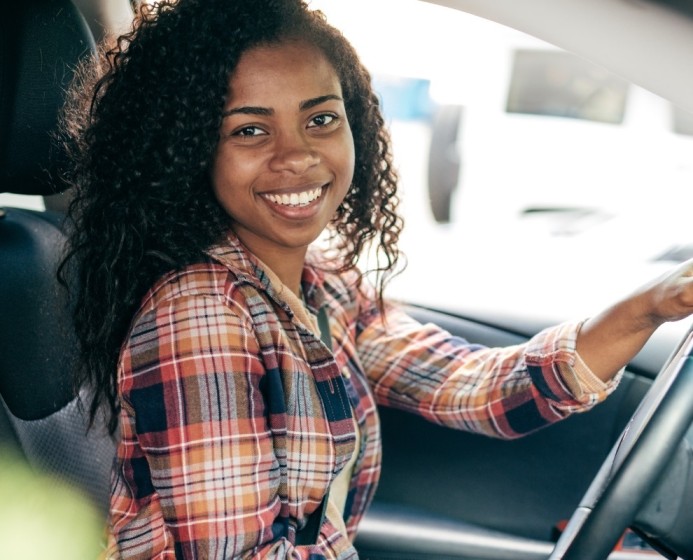 a girl in a car with hands on steering wheel